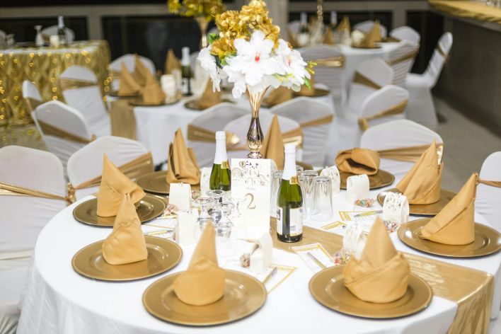 Beautifully decorated wedding reception table with golden accents and floral centerpiece.